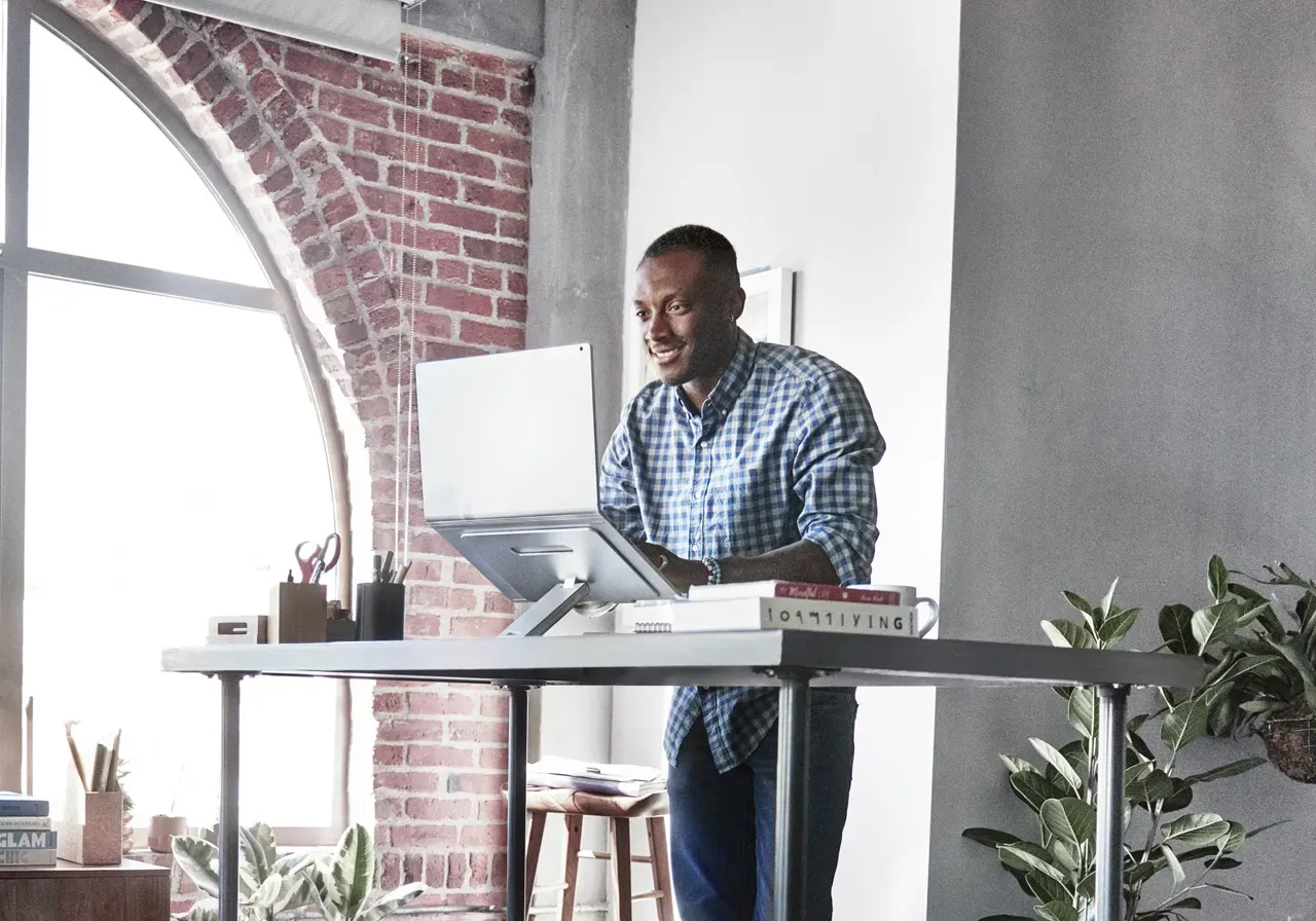 Man at a standing home office desk, and using laptop